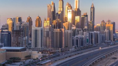 Dubai Yat Limanı günbatımı hava timelapse sırasında Birleşik Arap Emirlikleri kuleleri. Güneş gökdelenler uzun gölgeler ile yansıyan. Yolda trafik ile Jlt üzerinden üstten görünüm