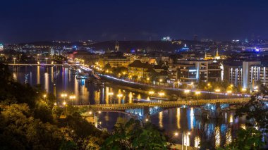 Prag 'daki Vltava Nehri' nin hava akşam manzarası ve trafik ile aydınlanan köprüler. Tekneler ve gemi suda yüzüyor. Hanavsky köşkünden üst görünüm