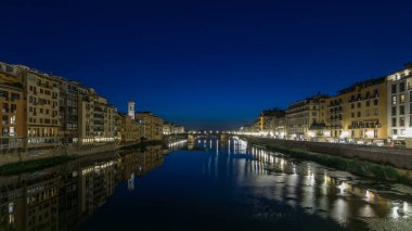 Ponte Santa Trinita 'nın (Kutsal Üçlü Köprü) alacakaranlık sahnesi günden geceye Arno Nehri üzerinde panoramik zaman geçişi günbatımından sonra su üzerindeki yansımalarla, eski evler yan yana. Floransa, İtalya