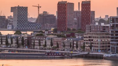 Hollanda, Rotterdam 'da gün batımında Katendrecht Yarımadası ve Maashaven Limanı' nın panoramik zaman çizelgesi. Şehir silueti, modern gökdelenler ve geleneksel Hollanda rıhtım evleri