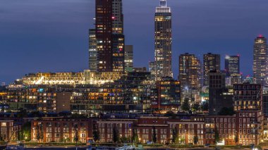 Rotterdam, Hollanda 'daki Katendrecht yarımadası ve Maashaven limanının hava ve gece geçiş zamanı. Şehir silueti modern gökdelenler ve geleneksel Hollanda rıhtım evleri