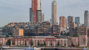 Rotterdam, Hollanda 'daki Katendrecht yarımadasının ve Maashaven limanının uçuş zamanı. Sabahları sıcak ışık, modern gökdelenler ve geleneksel Hollanda rıhtım evleri ile şehir silueti yükseliyor.
