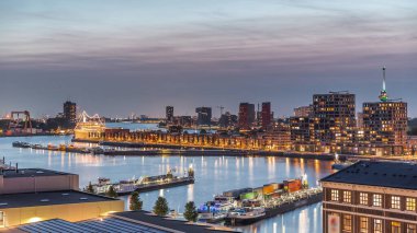 Rotterdam, Hollanda 'daki Katendrecht Yarımadası ve Maashaven Limanı' nın panoramik hava ve gece geçiş zamanı. Şehir silueti modern gökdelenler ve geleneksel Hollanda rıhtım evleri