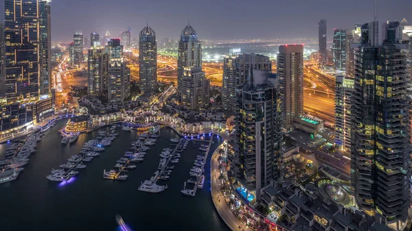 Dubai Marina'nın havadan üstten gündüz geceye geçiş saati. Dubai, Bae gün batımından sonra yüzen yatlar ve tekneler ile gezinti ve kanal. Işıklı modern kuleler ve yolda trafik