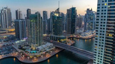 Dubai Marina gezinti güvertesi ve kanalı, gün batımından sonra Dubai, BAE 'de yüzen yat ve tekneler ile gündüz hava manzaralı. Modern kuleler, köprü ve trafik yukarıdan geliyor.