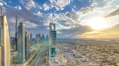 Dubai gökdelenleri, gün batımı akşam vakti. Dubai metro istasyonu ve Şeyh Zayed Yolu 'ndaki trafik. Kule çatısından gökyüzü görüntüsü. Güzel renkli bulutlu gökyüzü ve güneş ışığı