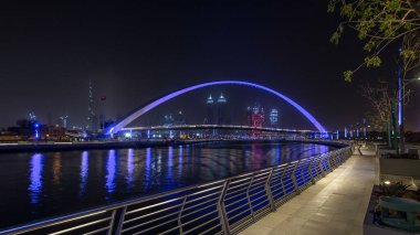 Dubai Su Kanalı gecesinde Dubai Deresi 'ni Jumeirah Sahili' ne bağlayan Dubai, Downtown Dubai ve Safa Parkı 'ndan geçen yaya köprüsü. Gökdelenlerin silueti. Birleşik Arap Emirlikleri