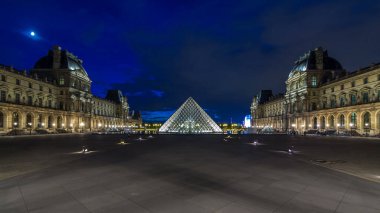 Louvre Müzesi piramidi, gün batımından geceye geçiş zamanı Paris, Fransa. Yaz gününde gökyüzü ne kadar da renkli. Meydanda yürüyen insanlar