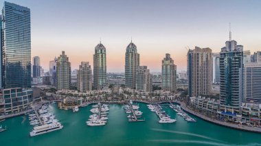 Dubai Marina gökdelenleri, hava zaman çizelgeleri, lüks yatları ve marina gezinti güvertesi olan liman, Dubai, Birleşik Arap Emirlikleri. Gölgeler gün batımında hareket eder