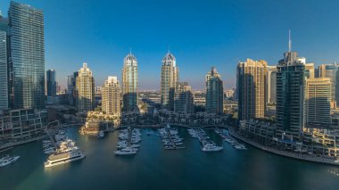 Dubai Marina gökdelenleri gün batımına kadar tüm gün boyunca gökdelenler, lüks yatlar ve marina gezinti güvertesi, Dubai, Birleşik Arap Emirlikleri. Gölge çok hızlı hareket eder. Mavi gökyüzü ve zümrüt su