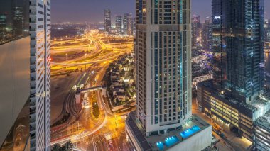 Havadan görünümü bir yol kavşak ve bir büyük şehir günde gece geçiş timelapse için modern kuleleri. Arabalar ve gökdelenler ile UAE Dubai Yat Limanı bölgesinin kentsel peyzaj.