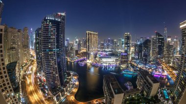 Dubai Marina 'nın gece gündüz aydınlanması. Hava geçiş panoramik zaman dilimi, BAE. Modern gökdelenler ve konut binaları. Yapay kanal şehrindeki alışveriş merkezinin yakınındaki yatlar ve tekneler.
