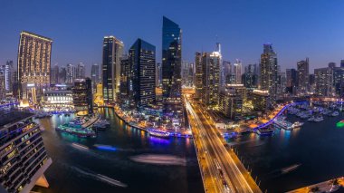 Dubai Marina gezinti güvertesi ve kanalı, gün batımından sonra Dubai, BAE 'de yüzen yat ve teknelerle panoramik hava manzaralı. Modern kuleler ve yoldaki trafik.