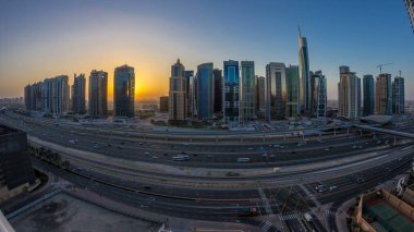 Jumeirah göl kulelerinin hava panoramik manzarası. Gece gündüz aydınlık gökdelenleri var. Şeyh zayed yolu ve metro hattında trafik var. Dubai marinasından güneş doğmadan önce çatı manzarası