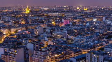 Paris 'teki evlerin çatılarının üstündeki hava panoraması gece gündüz geçiş zamanı. Günbatımından sonra aydınlanan kubbe ve diğer manzaralarla akşam manzarası