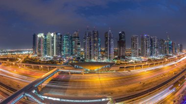 Dubai Limanı 'ndan Şeyh Zayed yoluna giden hava panoramik manzara. Dubai' deki Jlt aydınlatmalı gökdelenler, gece ve gündüz geçiş zamanı. Trafik, köprüler ve metro istasyonu. Birleşik Arap Emirlikleri