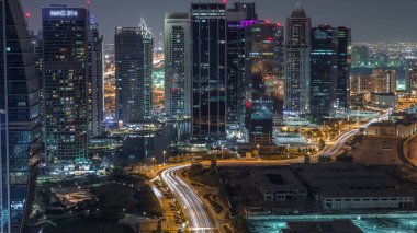 Jumeirah Lake Towers yerleşim bölgesi Dubai Marina yakınında gece geçiş timelapse gün havadan. Işıklı modern gökdelenler ve yukarıdan park