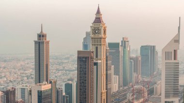 Sheikh Zayed Yolu yakınlarındaki binaların silueti ve Dubai, BAE 'deki hava trafiği gece gündüz değişiyor. Gündoğumundan önce finans merkezinde ve şehir merkezinde modern kuleler ve aydınlık gökdelenler