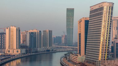 Gece gündüz kanal yakınlarındaki devasa gökdelenlerin hava görüntüsü Business Bay, Dubai, Birleşik Arap Emirlikleri 'ndeki geçiş zamanı..