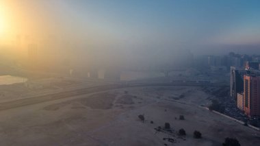 Abu Dabi şehrinin gökdelenleri aydınlanmadan önceki gökdelenleri gece gündüz geçiş zamanı. Çatıdan sisli bir sabahta hava manzarası