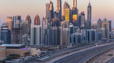 Dubai Yat Limanı günbatımı hava timelapse sırasında Birleşik Arap Emirlikleri kuleleri. Güneş gökdelenler uzun gölgeler ile yansıyan. Yolda trafik ile Jlt üzerinden üstten görünüm