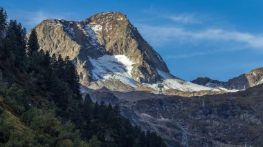 Alpler 'de güneş doğarken sabah görüşü etkileyici bir ışık ve bulutla. Tyrol, Avusturya. Ön planda çimenler ve kayalar aydınlandı. Biraz karlı Rocky dağları. Dağlardaki gölgeler