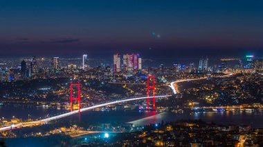 İstanbul kenti, Camlica Tepesi 'ndeki Bosphorus Köprüsü' nün (15 Temmuz Şehitleri) ve finans merkezinin havadan görünüşü günden geceye ufuk çizgisine bakıyor. Köprüde trafik ve Boğaz 'da gemi.