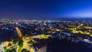 Porto 'nun eski kasabasının çatılarında panoramik hava manzarası sıcak bir bahar akşamında günden geceye geçiş, Porto, Portekiz. Işıklar yanıyor.