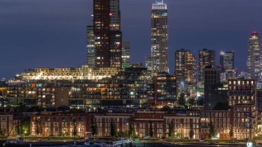Rotterdam, Hollanda 'daki Katendrecht yarımadası ve Maashaven limanının hava ve gece geçiş zamanı. Şehir silueti modern gökdelenler ve geleneksel Hollanda rıhtım evleri