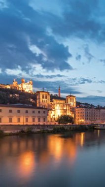 Aziz John 'un Vaftizci Katedrali ve Lyon' daki Notre-Dame de Fourviere Bazilikası 'nın zaman çizelgesi, günden geceye değişiyor. Yansıtılmış rıhtım ve nehirde yansıyan binalar. Fransa