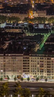 Geceleri Fourviere Hill 'den Lyon' un panoramik hava manzarası. Ufuk çizgisinde Rhone Nehri ve ikonik kent simgeleri yer alıyor. Evler çatılar ve caddelerde ve kavşaklarda trafik
