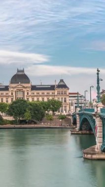 Fransa 'nın Lyon kentindeki Jean-Moulin Üniversitesi' nin yer aldığı Rhone Nehri 'nin panoramik hiperhızlandırılmış manzarası ve seti. Parçalı bulutlu bir gökyüzü zaman diliminin altında Üniversite Köprüsü ve rıhtımını içerir
