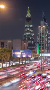 Riyad, Suudi Arabistan 'ın şehirsel gece zaman çizelgesinde aydınlık kuleler, gökdelenler, Kral Fahd Yolu ve yoğun trafik yer alıyor. Palmiyeler ve sokak lambaları şehrin içinden geçen ana otoyol boyunca uzanır..