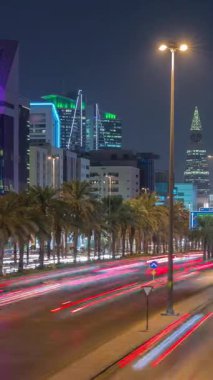 Riyad, Suudi Arabistan 'ın şehirsel gece zaman çizelgesinde aydınlık kuleler, cam gökdelenler, Kral Fahd Yolu ve yoğun trafik yer alıyor. Palmiyeler ve sokak lambaları şehrin içinden geçen ana otoyolda..