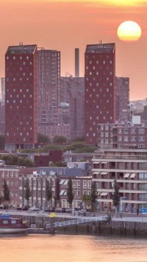 Hollanda, Rotterdam 'da gün batımında Katendrecht Yarımadası ve Maashaven Limanı' nın panoramik zaman çizelgesi. Şehir silueti, modern gökdelenler ve geleneksel Hollanda rıhtım evleri