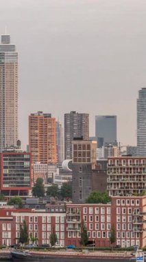 Rotterdam, Hollanda 'daki Katendrecht yarımadasının ve Maashaven limanının uçuş zamanı. Sabahları sıcak ışık, modern gökdelenler ve geleneksel Hollanda rıhtım evleri ile şehir silueti yükseliyor.