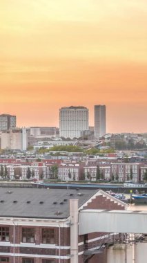 Günbatımında Rotterdam şehir merkezindeki modern binaların hava zaman çizelgesi, Hollanda. Finans bölgesinde kuleler ve gökdelenler, turuncu gökyüzü ile eski fabrika canlı bir ufuk çizgisi oluşturur