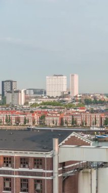 Rotterdam, Hollanda 'daki Katendrecht Yarımadası ve Maashaven Limanı' nın panoramik zaman çizelgesi. Sabah şehir silueti, modern gökdelenler ve Hollanda kıyısı evleri olan eski fabrikalar.