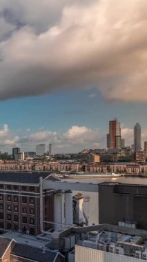 Arka planda Katendrecht ve Maas Nehri 'nin bulunduğu Maashaven üzerindeki hava zaman dilimi görüntüsü. Eski fabrika ofis ve etkinlik alanına dönüştü. Gökdelenlerin üzerinde dramatik bulutlu gökyüzü. Yollar boyunca trafik