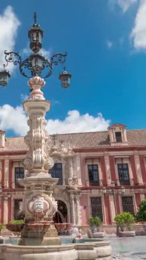 Sevilla Başpiskoposu ve Fuente Farola çeşmesi Plaza de Virgen de los Reyes şehir meydanı hiperhızlandırılmış zaman aralığı. Tarihi mimarisi olan mavi bulutlu bir gökyüzü. Sevilla, Endülüs, İspanya.