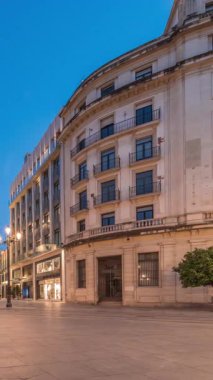 Avenida de la Constitucion, Seville, İspanya 'da günden geceye zaman dilimi. Modern sokak lambaları, yayalar ve kentsel atmosferi olan tarihi mimari. Iconic Adriatica binası gün batımından sonra parlıyor.