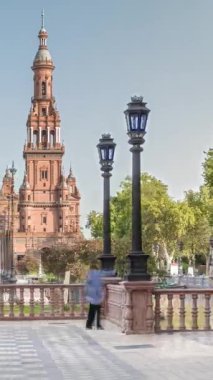 Seville 'de Espana Plaza de Espana, Ibero-American Exposition için inşa edilen Maria Luisa Park' taki büyük mimari kompleksin kulesi. Ağaçlar, kanallar ve mavi gökyüzünün altındaki klasik sokak lambaları.