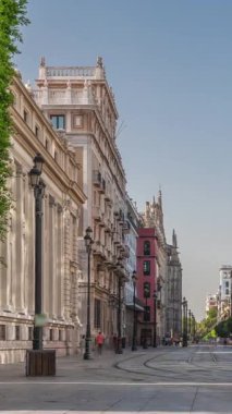 Avda boyunca yürüyen yayalar. De la Constitucion, Seville, İspanya 'nın Casco Antiguo bölgesindeki ana cadde. Edificio de la Adriatica yakınlarındaki zaman dilimi, tarihi binalar ve geçen tramvaylar