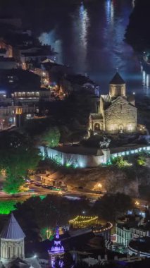 Metekhi Bakire Meryem Varsayımı Kilisesi 'nin hava gece zaman çizelgesi ve Kura Nehri üzerindeki Kral Vakhtang Gorgasali Heykeli. Köprüde trafik vardı ve rıhtım aydınlatılmıştı. Tiflis, Gürcistan.