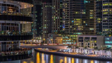Dubai Marina rıhtımı kuleleri ve Dubai 'deki alışveriş merkezinin balkonundan restoranlara yakın köprüsü olan Birleşik Arap Emirlikleri hava geçiş zamanı..