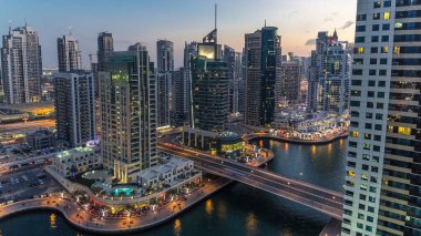 Dubai Marina gezinti güvertesi ve kanalı, gün batımından sonra Dubai, BAE 'de yüzen yat ve tekneler ile gündüz hava manzaralı. Modern kuleler, köprü ve trafik yukarıdan geliyor.