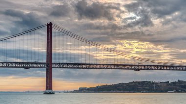 Lisbon city sunrise with April 25 bridge timelapse, River and waterfront early morning. Orange clouds on the sky