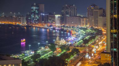 Dubai creek peyzaj gün gece geçiş timelapse tekneler ve yatlar ile ve trafik yol ve otopark ile modern binalar. Yukarıdan hava üstten görünüm