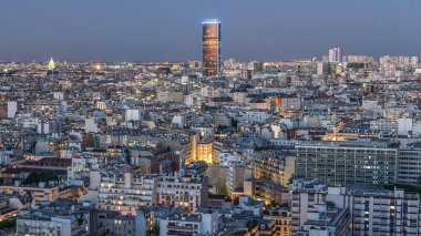 Paris 'teki evlerin çatılarının üstündeki hava panoraması gece gündüz geçiş zamanı. Günbatımından sonra aydınlatılan ana manzaralarla akşam manzarası