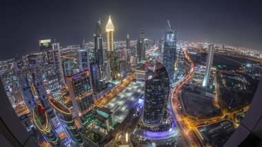 Sheikh Zayed Yolu yakınlarındaki binaların silueti ve Dubai, BAE 'deki hava gününden geceye geçiş. Günbatımından sonra finans merkezinde ve şehir merkezinde park yeri olan modern kuleler ve gökdelenler.
